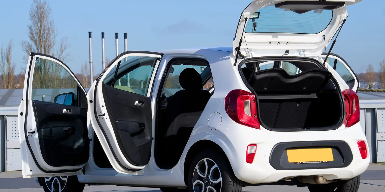 Carro compacto branco com portas e porta-malas abertos