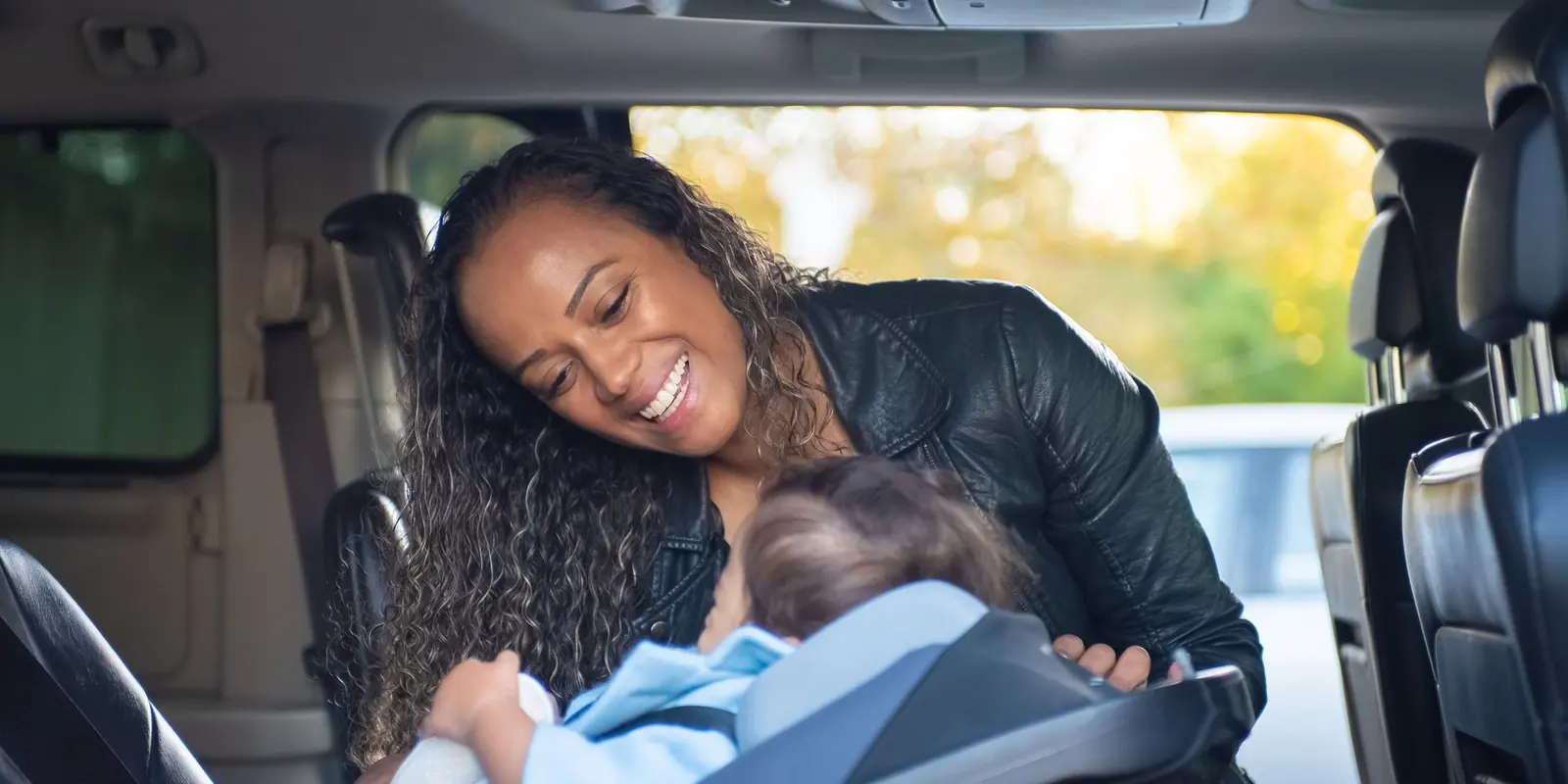 Mãe sorrindo para o bebê sentado na cadeirinha do carro